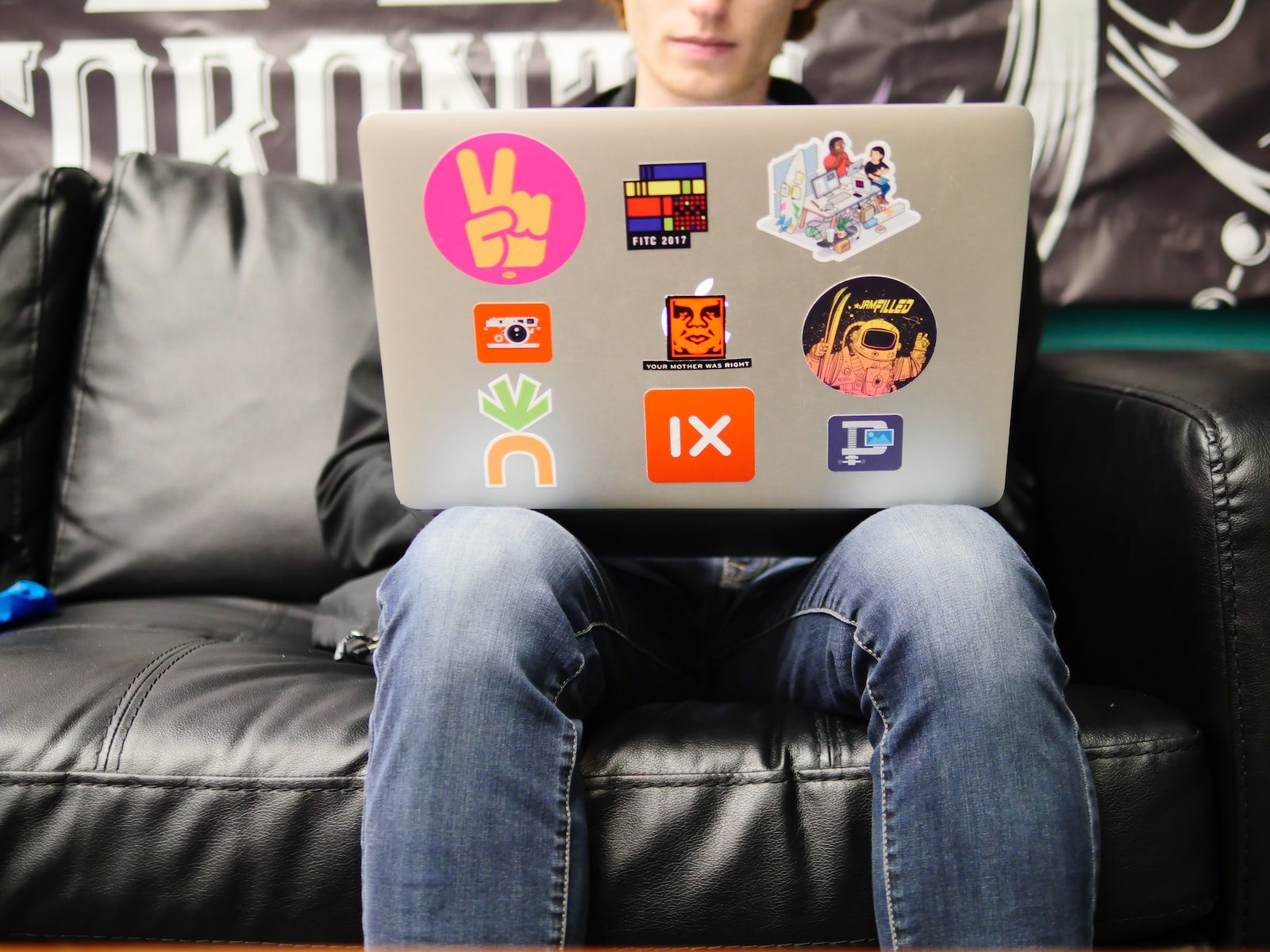 man using silver MacBook sitting on black leather sofa